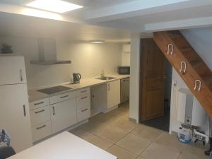 a large kitchen with white cabinets and a staircase at Spacious fullyequipped houses in Vordingborg
