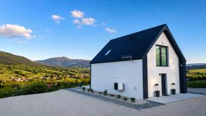 a small white house with a black roof at Beskid Island in Dobra