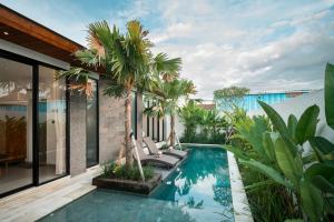 an outdoor pool with palm trees and a house at Snuggy Shack Villas in Munggu