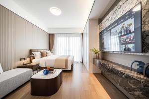 a hotel room with a bed and a flat screen tv at Ruilan Courtyard in Shenzhen