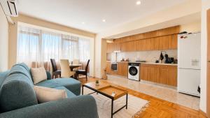 a living room with a blue couch and a kitchen at Boris Garden Comfort Suite in Burgas