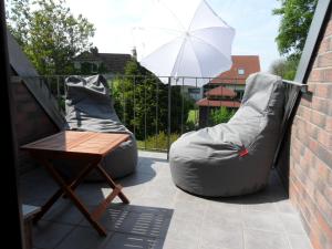 um pátio com dois sacos de feijão, uma mesa e um guarda-chuva em Appartement bei Kiel em Lilienthal