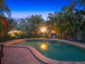 a large swimming pool in a yard with trees at Stunning Sea Facing Bayside House with Pool in Birkdale