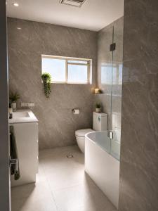 a bathroom with a tub and a toilet and a sink at Stunning Sea Facing Bayside House with Pool in Birkdale +6 photos
