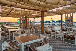 a restaurant on the beach with tables and chairs at Hilton Alexandria Corniche Hotel in Alexandria