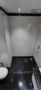 a bathroom with a white toilet and a black floor at Hotel bindu in Ghāzīpur