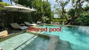a swimming pool with two chairs and an umbrella at Modern House Uprompt Chiangmai in Chiang Mai