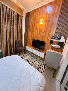 a hotel room with a bed and a tv at Mario Suites Ltd in Kano