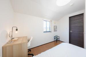 a bedroom with a bed and a desk and a door at FUJIMI TOWN HOUSE in Tokyo