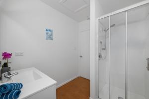 a white bathroom with a shower and a sink at Sea-Renity Picton, Apt B in Picton +9 photos