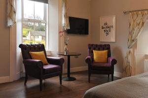 een slaapkamer met 2 stoelen, een tafel en een tv bij The Gateway Lodge in Donegal