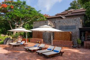 a group of lounge chairs and umbrellas on a patio at Victoria Nui Sam Lodge in Chau Doc