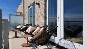 a row of chairs with pillows on a balcony at Residentie De Zeester | De Wulk in Scherpenisse