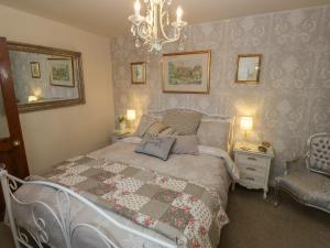 a bedroom with a bed and a chandelier and a chair at Prospect Cottage in Sowerby Bridge