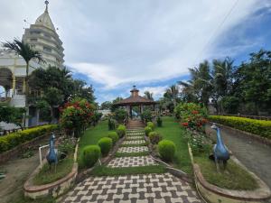 a garden with statues of peacocks and a gazebo at Lokenath Resort in Tarapith