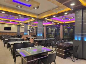a dining room with tables and chairs and purple lights at Lokenath Resort in Tarapith