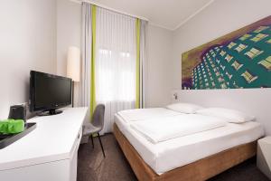 a hotel room with a bed and a flat screen tv at Wyndham Garden Düsseldorf City Centre Königsallee in Düsseldorf