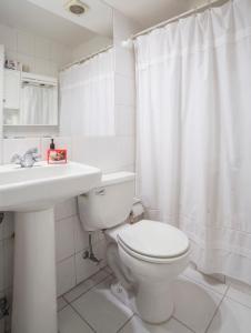 a white bathroom with a toilet and a sink at Departamento Metro Simón Bolívar in Santiago