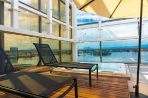 a room with a chair and a table and windows at Novotel RJ Porto Atlantico in Rio de Janeiro