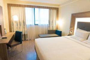 a hotel room with a large white bed and a desk at Novotel RJ Porto Atlantico in Rio de Janeiro