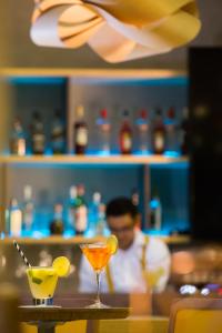 a man sitting at a bar with two cocktails on a table at Novotel RJ Porto Atlantico in Rio de Janeiro