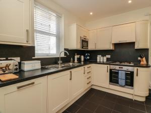 a kitchen with white cabinets and a sink at Haven Cottage in Kirkcudbright