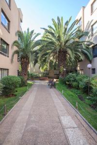 a walkway with two palm trees next to a building at Departamento Metro Simón Bolívar in Santiago