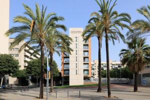a group of palm trees in front of a building at Catalonia Barcelona Beach in Barcelona