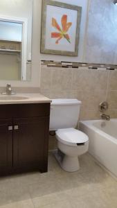 a bathroom with a toilet and a sink and a tub at Trailsman Lodge in Baddeck
