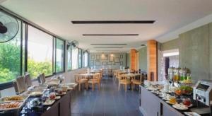 a dining room with tables and chairs and windows at Lipda Resort in Ban Nong Hin