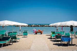 a group of chairs and umbrellas on a beach at Amare Suite & Apartments in Bellaria-Igea Marina