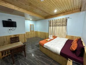 a bedroom with a bed and a tv and a bench at Hill Ice Guesthouse & Cafe - Mountain View & Balcony, Tosh in Tosh