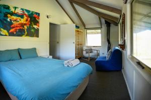 a bedroom with a blue bed and a chair at Alpzview Guesthouse in Tawonga