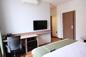 a bedroom with a bed and a desk with a television at Trevon Hotel Gujrat Centrale, Ranchi in Rānchī