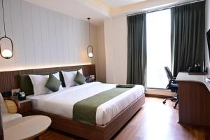 a hotel room with a large bed and a desk at Trevon Hotel Gujrat Centrale, Ranchi in Rānchī +38 photos