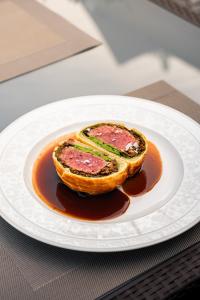 a plate with a piece of bread with meat and sauce at Villa Patriot Boutique Hotel in Mariánské Lázně