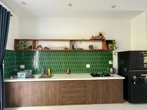 a kitchen with green tile and a black refrigerator at An Bang Chic Villa Nguyên Căn in Tân Thành (1) +5 photos