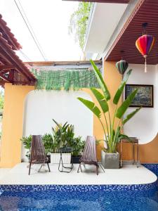 a swimming pool with two chairs and a plant at An Bang Chic Villa Nguyên Căn in Tân Thành (1)