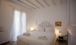 a white bedroom with a white bed with towels on it at Mykonian Style w Shared Pool Houses 8 & 9 in Ornos +20 photos