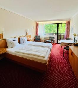 a hotel room with a large bed and a large window at Gästehaus Huber - Hotel Garni in Bad Füssing