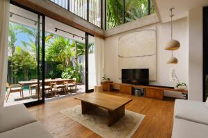 a living room with a television and a table at Villa Pakuk by Alfred in Bali in Canggu