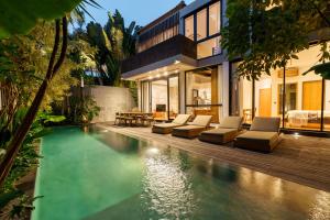 a house with a swimming pool next to a house at Villa Pakuk by Alfred in Bali in Canggu