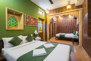 a bedroom with a large white bed with green walls at Guesthouse Tofu- Fort View in Jaisalmer