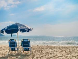 two chairs and an umbrella on a beach at Grand Mercure Rio de Janeiro Copacabana in Rio de Janeiro