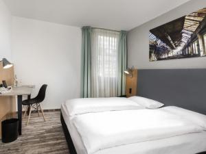 a hotel room with two beds and a desk at ibis Styles Hotel Gelsenkirchen in Gelsenkirchen