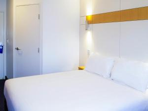 a bedroom with a large white bed and a door at ibis Budget - Gosford in Gosford