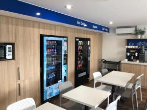 a restaurant with tables and chairs and a drink machine at ibis Budget - Gosford in Gosford