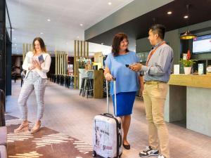 two women and a man with a suitcase in a store at ibis Baden Neuenhof in Baden