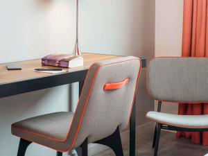an office desk with two chairs and a table with a vase at Adagio Paris 19ème Cité de la Musique in Paris