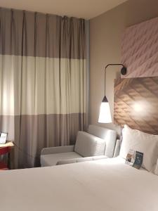 a hotel room with a bed and a chair at ibis Carlos Barbosa in Carlos Barbosa +62 photos